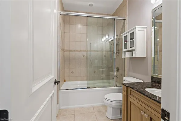 a bathroom with a granite countertop bathtub shower sink mirror and toilet