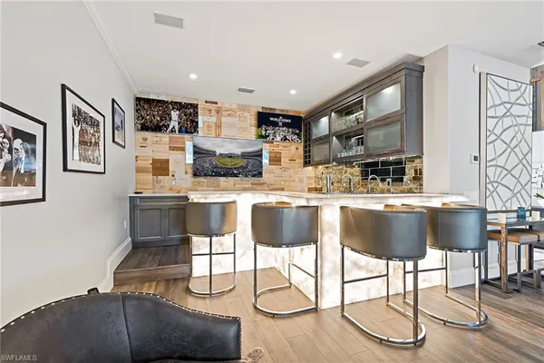 a kitchen with stainless steel appliances kitchen island granite countertop a dining table chairs and a refrigerator