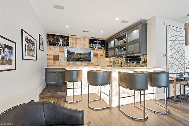 a kitchen with stainless steel appliances kitchen island granite countertop a dining table chairs and a refrigerator