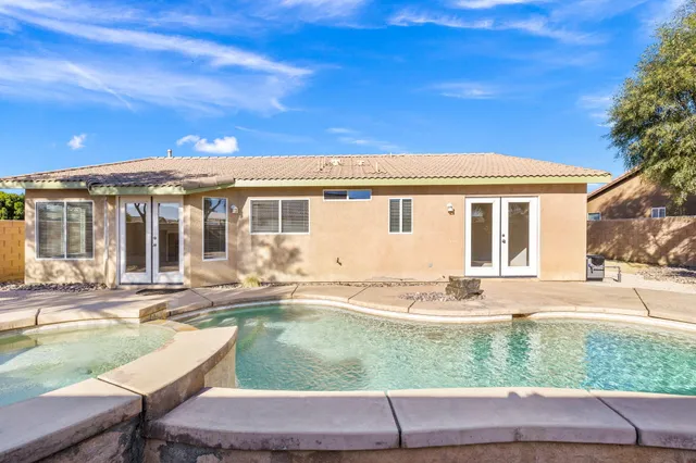 a view of a white house next to a yard with lawn chairs