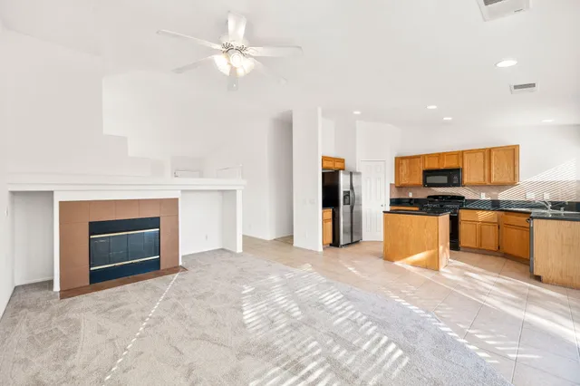 a kitchen with stainless steel appliances kitchen island granite countertop a refrigerator a stove a sink and a dining table with white cabinets