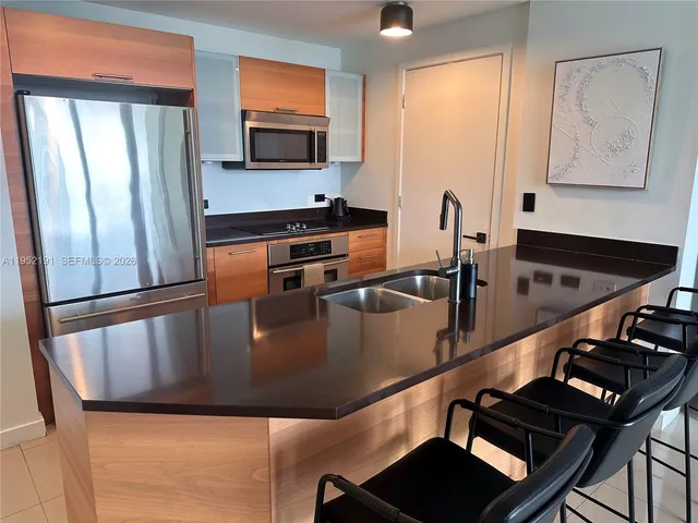 a kitchen with stainless steel appliances granite countertop a refrigerator a stove and a sink with wooden floor