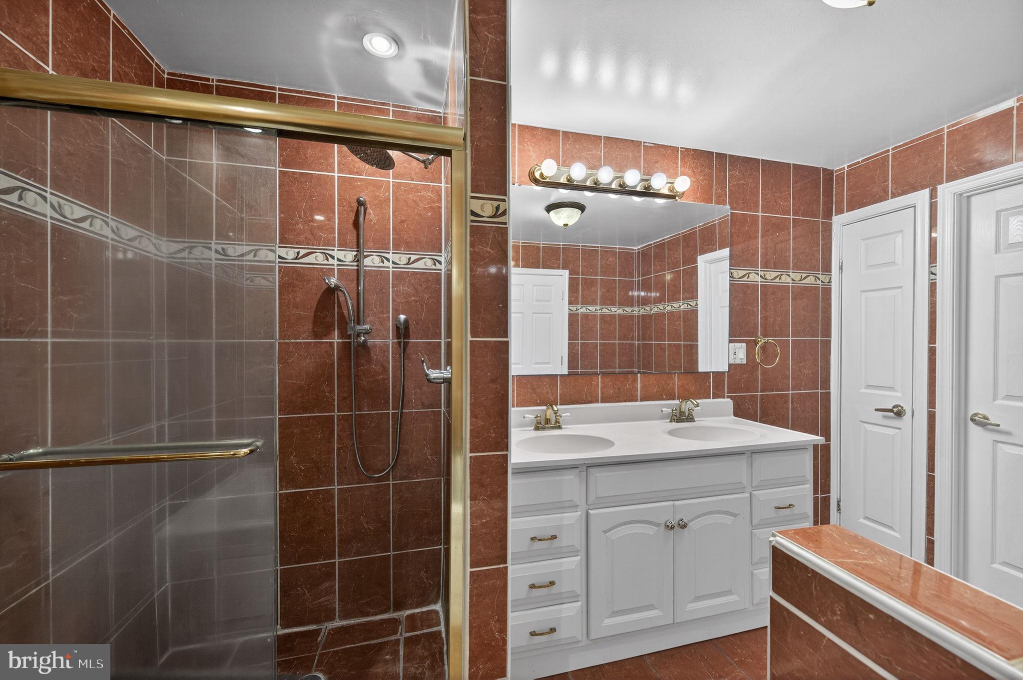 10600 Vantage Court Potomac, MD 20854 - Photo 62 of 91 a bathroom with a double vanity sink a toilet a mirror and shower