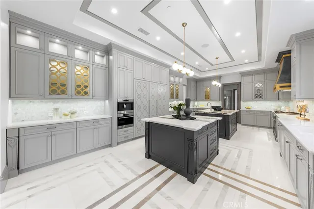 a large white kitchen with a large counter top a sink stainless steel appliances and cabinets
