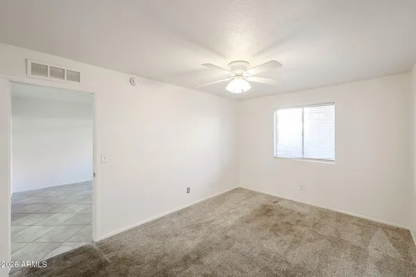 an empty room with a window and a ceiling fan