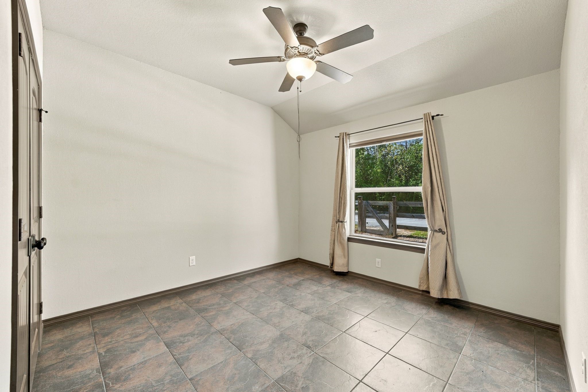 7049 Pine Shadows Road Cleveland, TX 77328 - Photo 28 of 49 Bright and airy room featuring a ceiling fan, large window with curtains, and elegant tile flooring.