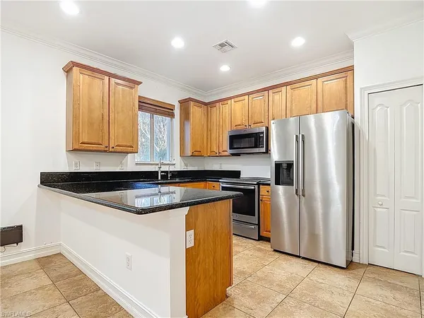 a large kitchen with stainless steel appliances kitchen island granite countertop a refrigerator and a sink