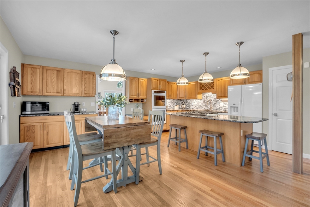133 Nashaway Road Bolton, MA 01740 - Photo 11 of 42 a kitchen with stainless steel appliances kitchen island granite countertop a table chairs and a white cabinets
