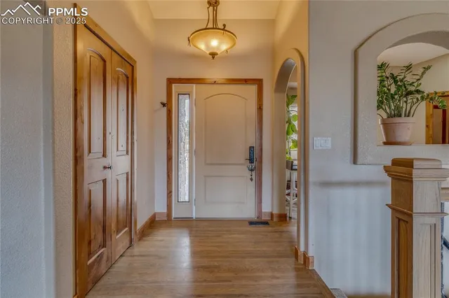 a view of a hallway with wooden floor and chandelier