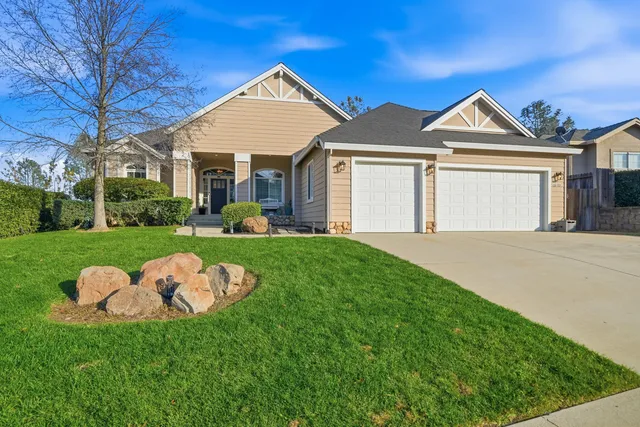a view of a white house next to a yard and a large tree
