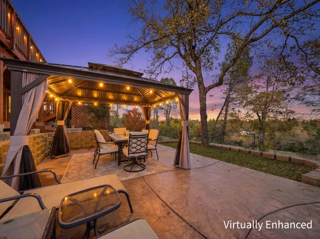 a view of a patio with table and chairs under an umbrella with a tree