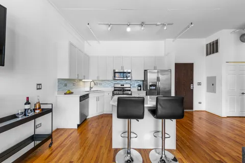 a kitchen with stainless steel appliances a stove a refrigerator and white cabinets with wooden floor