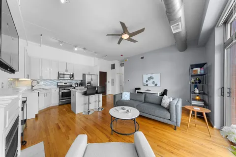 a living room with stainless steel appliances furniture and a view of kitchen