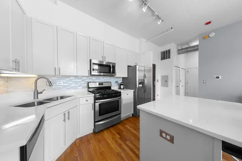 a kitchen with stainless steel appliances a sink stove refrigerator and cabinets