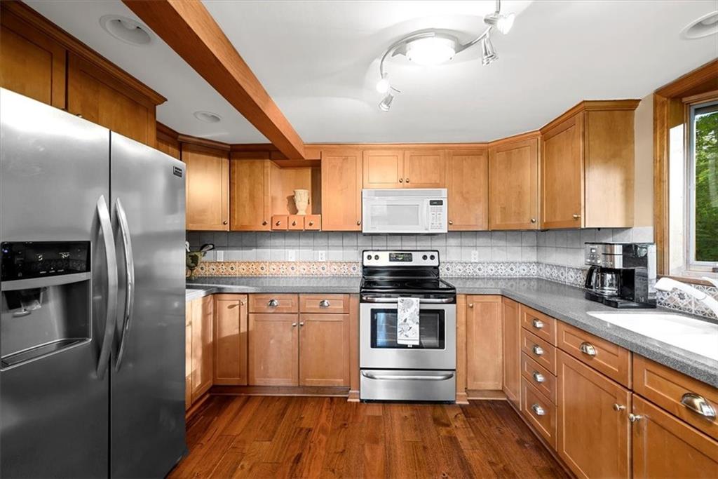 228 Foxglove Road Baden, PA 15005 - Photo 8 of 25 a kitchen with stainless steel appliances granite countertop a refrigerator a sink dishwasher a stove and white countertops with wooden floor