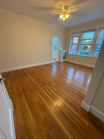 a view of an empty room with window and wooden floor