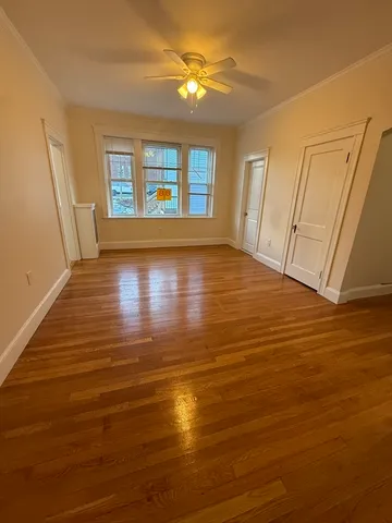 a view of an empty room with window and wooden floor