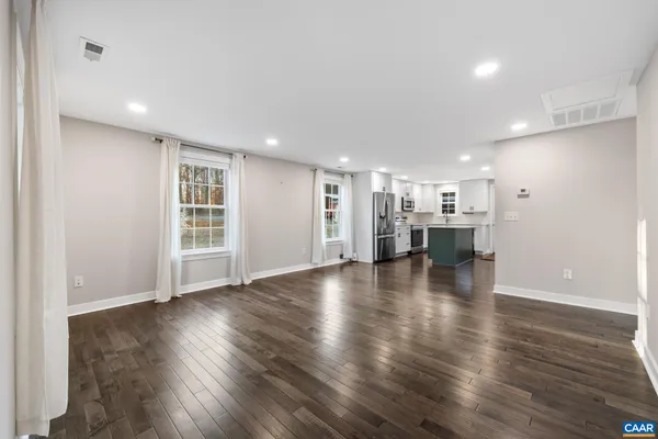 a view of empty room with kitchen and window