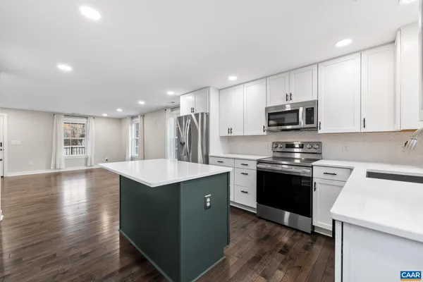 a kitchen with stainless steel appliances kitchen island a sink dishwasher a stove and a refrigerator with wooden floor