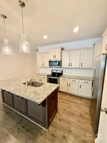 a large kitchen with stainless steel appliances kitchen island granite countertop a refrigerator a sink and a stove