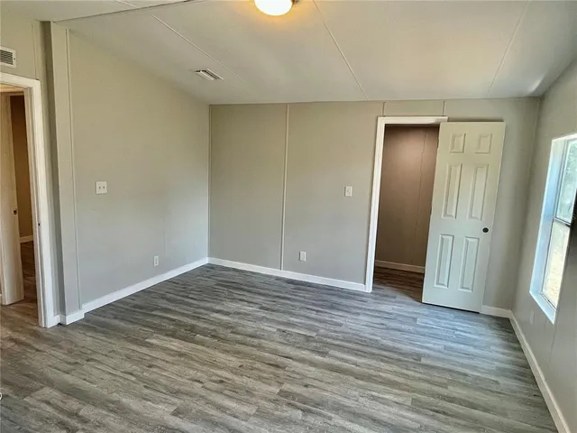 a view of an empty room with wooden floor and window