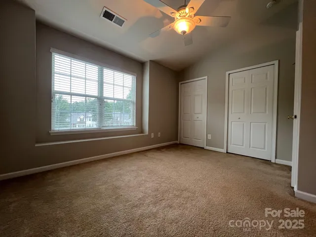 an empty room with windows and chandelier fan