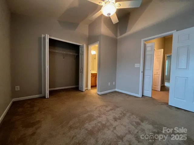 an empty room with a chandelier fan and a bathroom