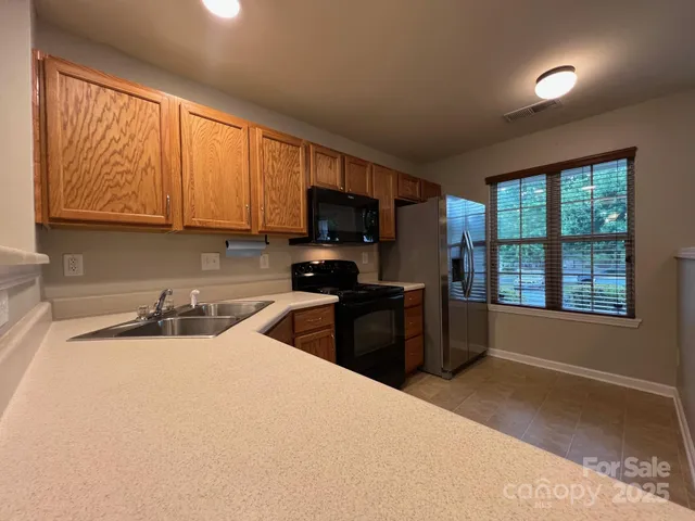 a kitchen with a sink wooden cabinets and a window