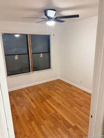 a view of an empty room with a chandelier fan and a window