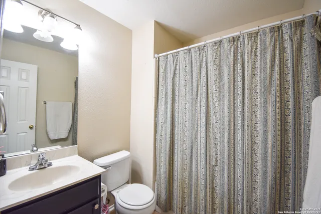 a bathroom with a toilet a sink and curtain