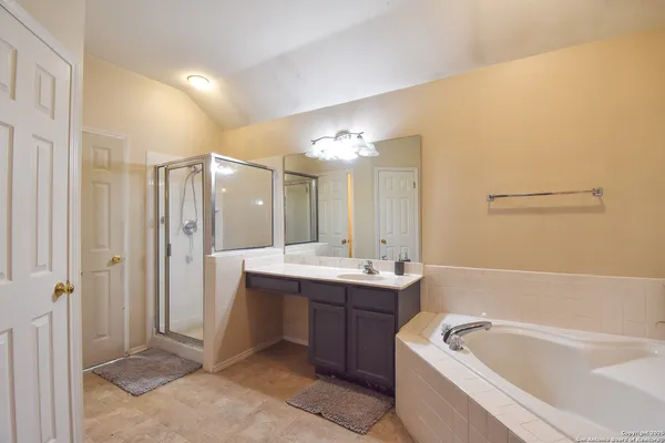 a bathroom with a bathtub a double vanity sink and mirror