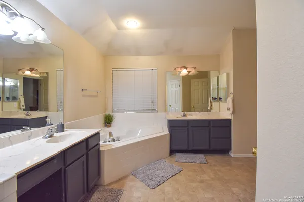 a bathroom with a tub a double vanity sink and mirror