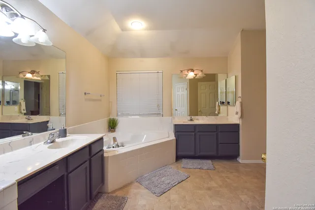 a bathroom with a tub a double vanity sink and mirror