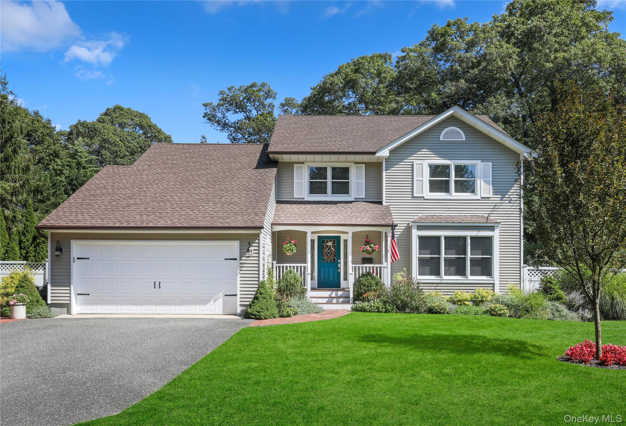 Traditional-style house featuring a shingled roof, covered porch, asphalt driveway, and a garage