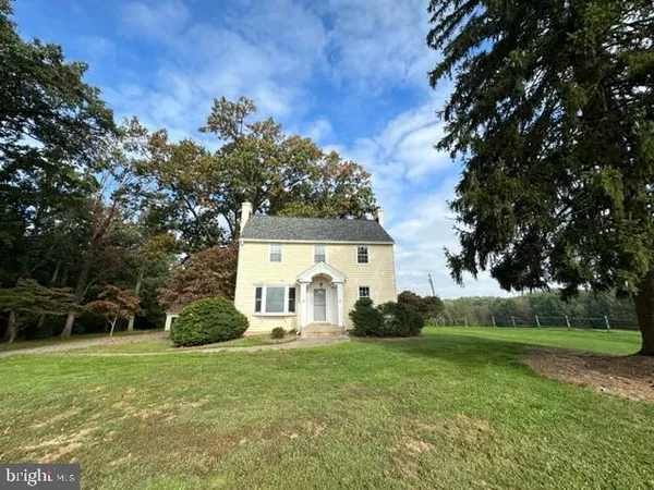 a view of a white house with a big yard and large trees