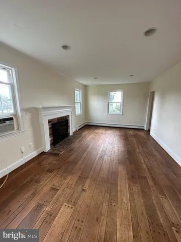 an empty room with wooden floor fireplace and windows