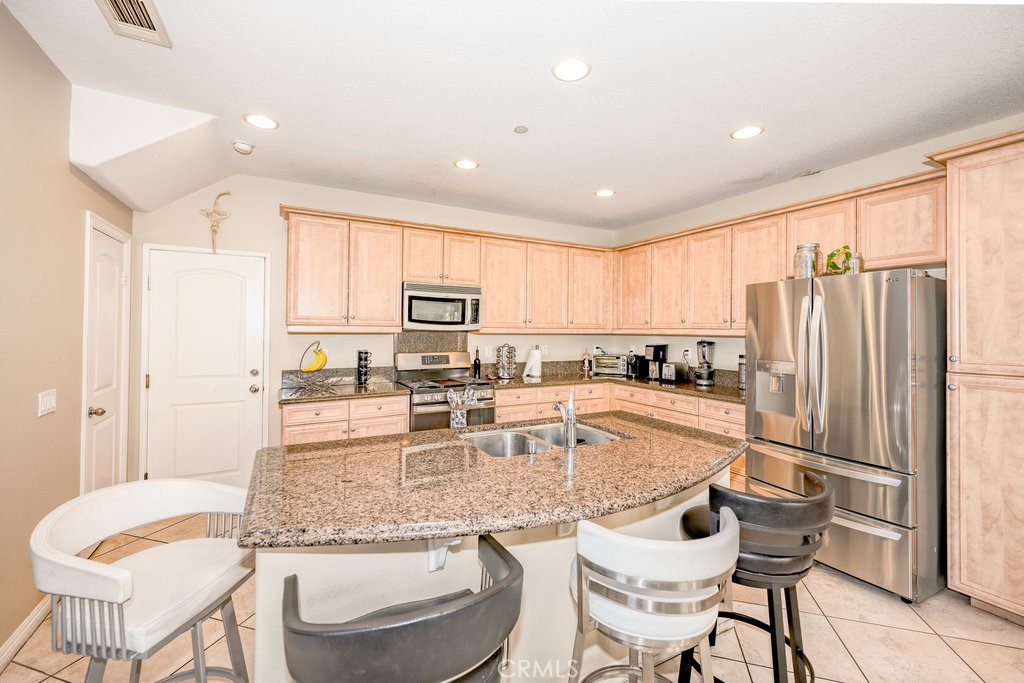 3631 Dunkirk Drive Oxnard, CA 93035 - Photo 8 of 16 a kitchen with stainless steel appliances granite countertop a refrigerator a stove a sink and white cabinets with wooden floors