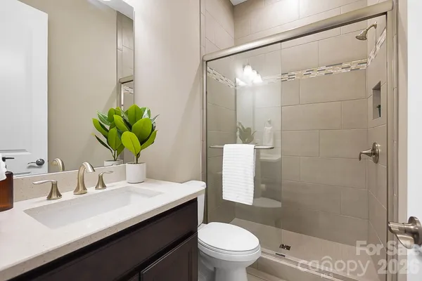 a bathroom with a sink a toilet a mirror and shower