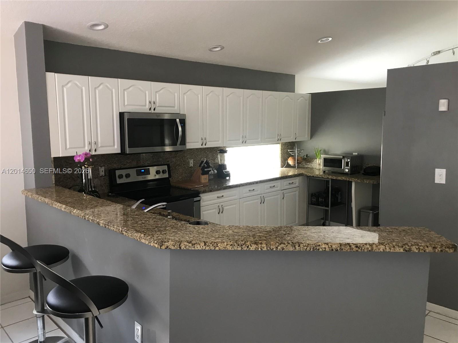 16654 Southwest 103rd Lane Miami, FL 33196 - Photo 5 of 20 a kitchen with granite countertop a sink stainless steel appliances and cabinets