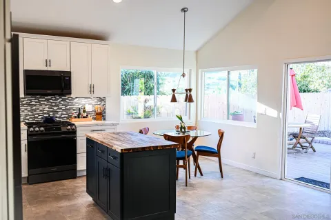 a kitchen with stainless steel appliances granite countertop a stove a refrigerator a sink a dining table and chairs with wooden floor