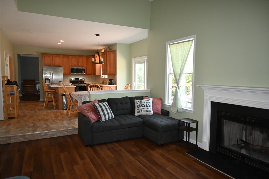 3829 East Hopewell Road Center Valley, PA 18034 - Photo 9 of 52 An inviting open-concept living space features warm wood flooring and a classic fireplace, flowing into a functional kitchen.