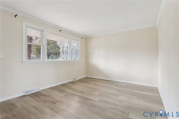 an empty room with wooden floor and windows