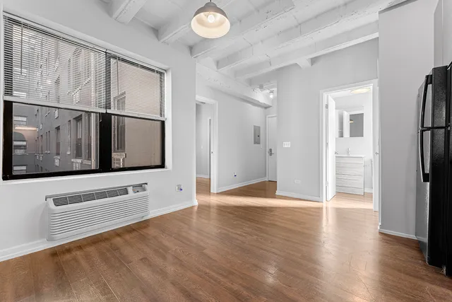 a view of an empty room with wooden floor and a window