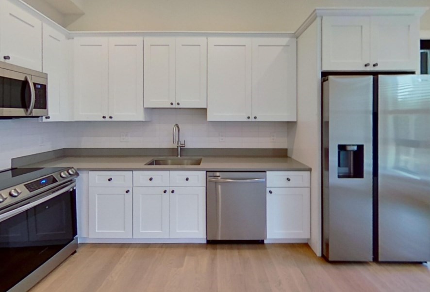 a kitchen with stainless steel appliances granite countertop a refrigerator a stove a microwave and white cabinets