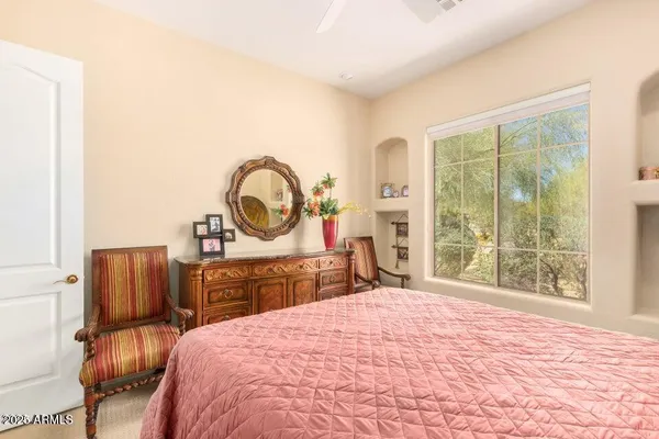 a bedroom with a bed a mirror on dresser and a large window