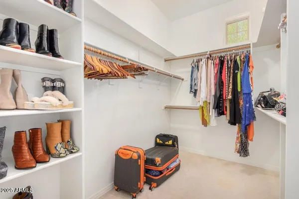 a view of walk in closet with clothes and shoes