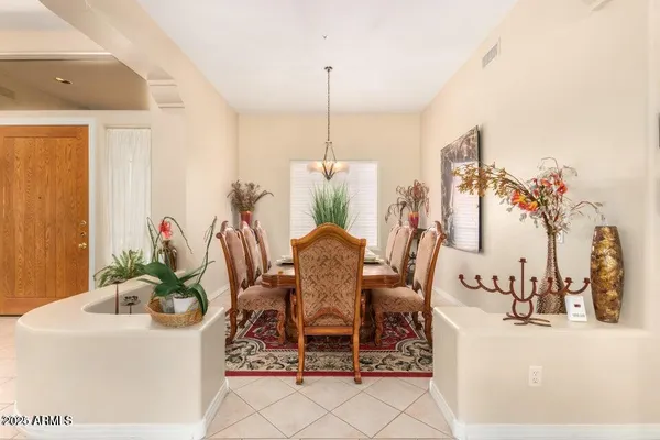 a dining room table with chairs and potted plants