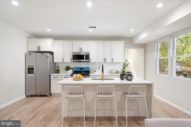 a kitchen with stainless steel appliances a refrigerator a stove a dining table and chairs