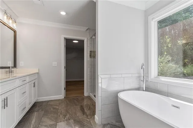 a bathroom with a double vanity sink a toilet a window and tub