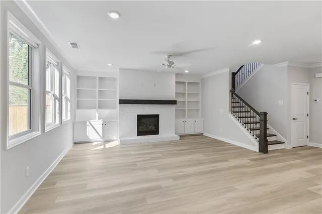 an empty room with wooden floor fireplace and windows